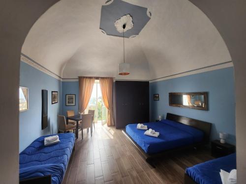 a bedroom with two blue beds and a dining room at La Pennichella Sorrentina Relais in Meta