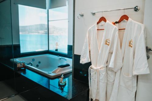 a bathroom with white towels hanging on a rack next to a tub at Hotel Boutique Coração Aberto in Capitólio