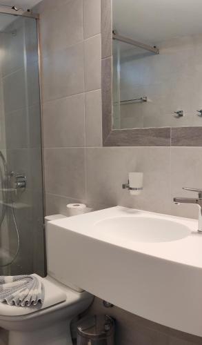 a bathroom with a sink and a toilet and a mirror at Evelin hotel in Pythagoreio