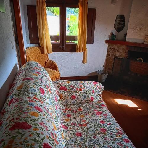 a bed in a room with a flowered blanket on it at Masia Can Constans in Queralbs