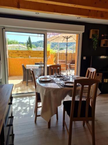 une salle à manger avec une table et des chaises et une fenêtre dans l'établissement Maison classée 2 étoiles proche du lac du Salagou, à Clermont-lʼHérault