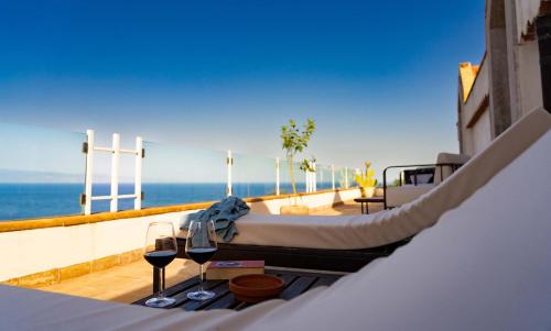 a balcony with a bed and two glasses of wine at Villa Zagara Garden Spectacular Sea View in Taormina in Taormina