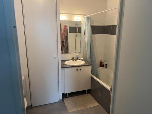 e bagno con lavandino, specchio e vasca. di Joli appartement T2 a Montpellier