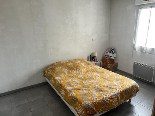 uma cama num quarto com um cobertor amarelo em Joli appartement T2 em Montpellier