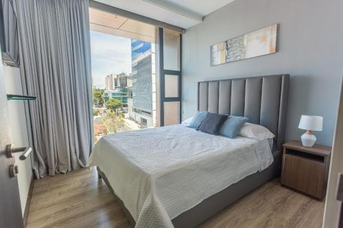um quarto com uma cama e uma grande janela em Escape to this Rooftop Jacuzzi Apartment em Vuelta del Virilla