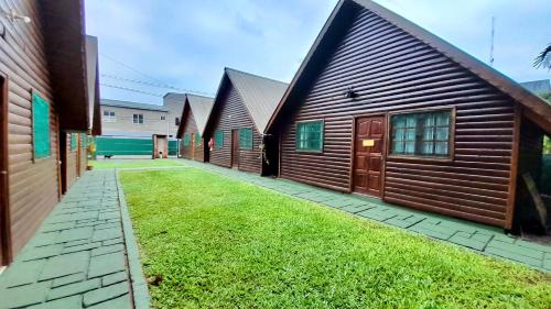 a row of wooden buildings with a grass yard at Cabanas MERALE Excelente Ubicacion in Puerto Iguazú