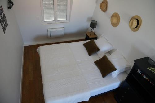 Schlafzimmer mit einem Bett mit weißer Bettwäsche und Kissen in der Unterkunft Les suites de la villa Margaux in Bezons