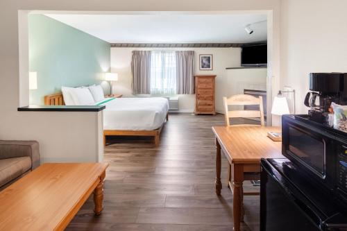 une chambre d'hôtel avec un lit et une table dans l'établissement GuestHouse Inn & Suites Kelso/Longview, à Kelso