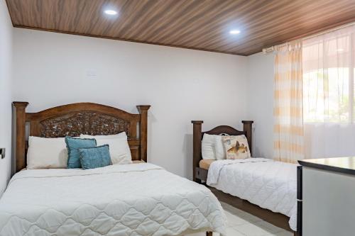 1 dormitorio con 2 camas y ventana en Family 2bd apt near Quepos/Manuel Antonio, en Quepos