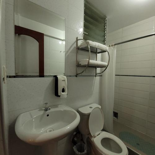 a white bathroom with a sink and a toilet at Hotel Ruta Amazónica Machupicchu in Machu Picchu