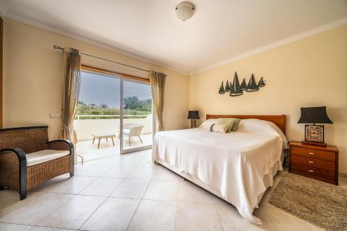 sypialnia z łóżkiem, krzesłem i oknem w obiekcie Luxury 4 bed villa with private pool Oasis Parque, Alvor AT16 w mieście Portimão