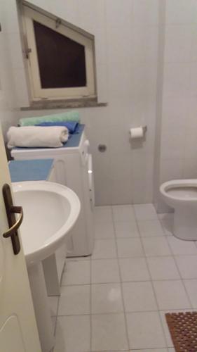 bagno bianco con lavandino e servizi igienici di trilocale "Alicudi" in Portorosa a Furnari