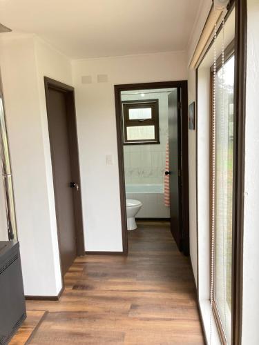 a hallway with a bathroom with a toilet and a door at Cabañas Casatur para 6 personas en Ancud Chiloe in Ancud
