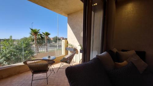 uma sala de estar com uma varanda com uma mesa e cadeiras em Luxury F3 appartment Les Orangers em Marrakech