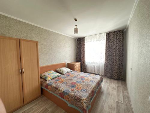 una piccola camera con letto e finestra di Назарбаева 204 a Pavlodar