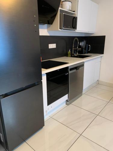 Il comprend une cuisine équipée d'un réfrigérateur noir et de placards blancs. dans l'établissement KIFKIF entrée autonome boîte à clef, à Saint-Germain-lès-Arpajon