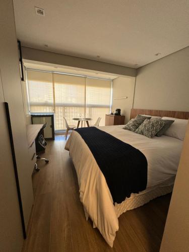 a bedroom with a large bed and a table at 915 Lux Studio Allianz Park in Sao Paulo