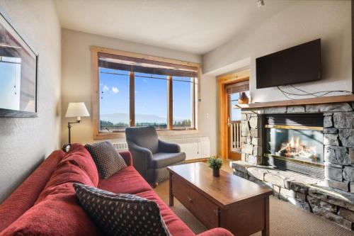 a living room with a red couch and a fireplace at Morning Eagle 209 in Whitefish