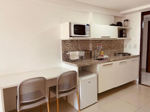 uma pequena cozinha com uma mesa e um micro-ondas em Aptos super confortáveis no Gold Flat by Apartamentos Jampa em João Pessoa