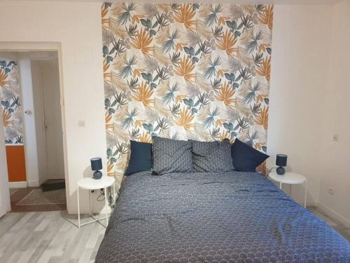 sypialnia z niebieskim łóżkiem z zagłówkiem kwiatowym w obiekcie Le Nénuphar w mieście Cambrai