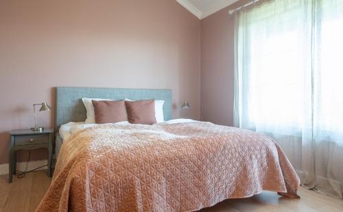 a bedroom with a bed with a pink blanket and a window at Kollen Slottet in Oslo