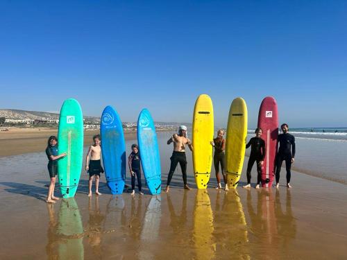 een groep mensen die hun surfplanken op het strand houden bij Superbe appartement , grande terrasse vue mer et montagne Taghazout in Taghazout