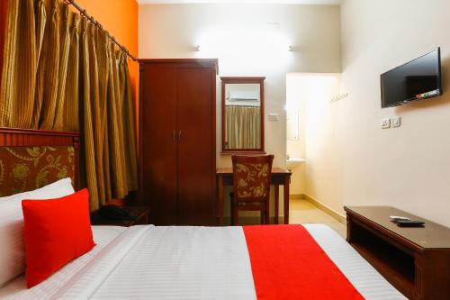 a bedroom with a bed and a desk and a television at Collection O Mamieyaar Veedu in Chennai