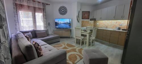 ein Wohnzimmer mit einem Sofa und einer Küche in der Unterkunft Fjori's Apartment in Korçë