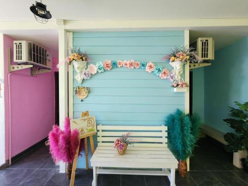 a bench in front of a blue wall with feathers at ลิตเติ้ลโฮม ที่พักเพชรบุรี in Phetchaburi