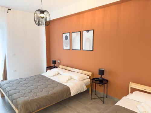 two beds in a bedroom with orange walls at Wolf House BnB in Coppito