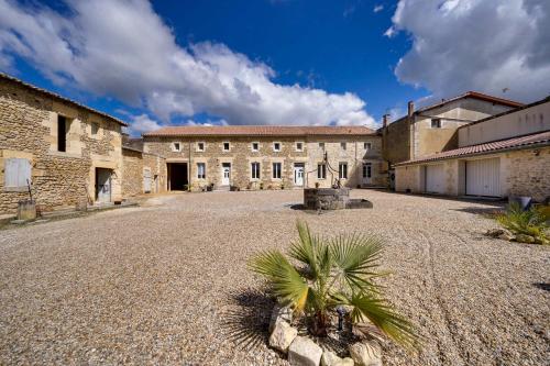un vieux bâtiment avec un palmier devant lui dans l'établissement La quiétude de Jonzac, à Saint-Ciers-sur-Gironde