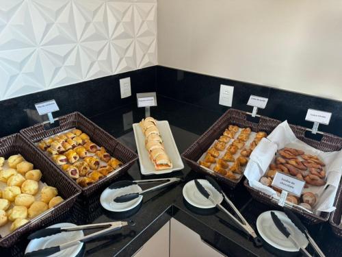 three baskets of different types of donuts on a counter at Visionsul Hotel in Chapadão do Sul