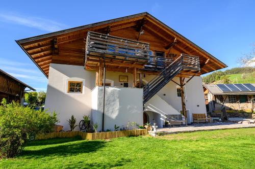a house with a wooden roof and a yard at Labe Biohof Oberzonn in Kastelruth
