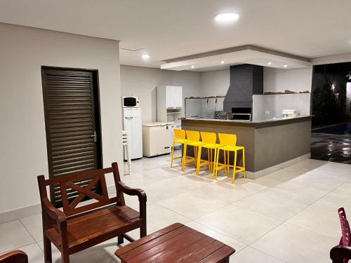 a living room with yellow chairs and a kitchen at Casa em Campo Grande com piscina in Campo Grande