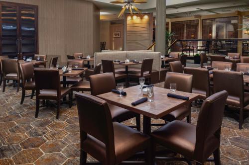 a dining room with wooden tables and chairs at DoubleTree by Hilton Kansas City - Overland Park in Overland Park