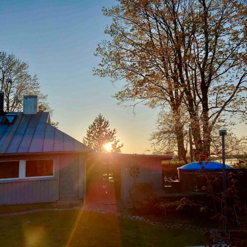 a house with the sun setting behind it at Širvėnos namai - penkiavietis numeris in Biržai