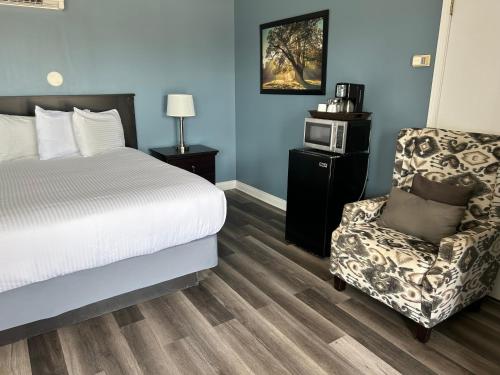 a bedroom with a bed and a chair and a microwave at Middleton Motel & Suites in Middleton