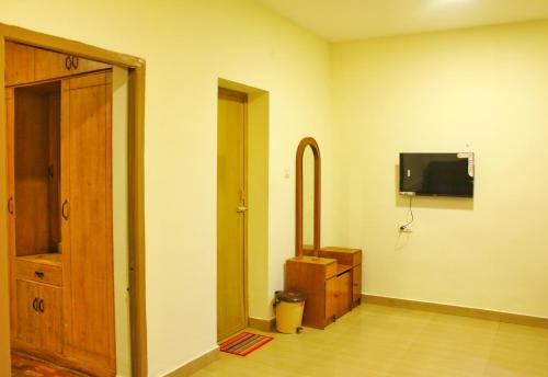 a room with a tv on the wall and a door at Ooty AR Residency in Ooty