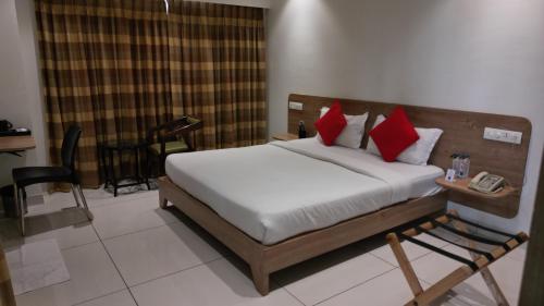 a bedroom with a bed with red pillows at Sapphero Akshar Inn- Jamnagar in Jamnagar