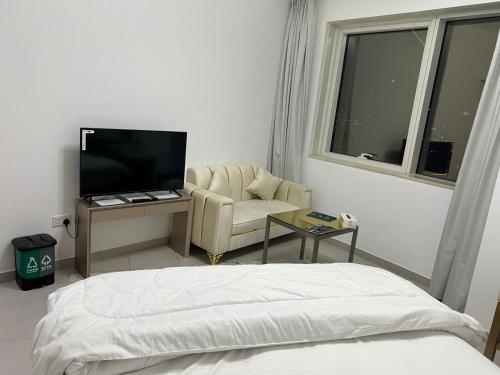 a bedroom with a bed and a chair and a television at Dubai Entire Serviced Room Unit Excellence in Dubai