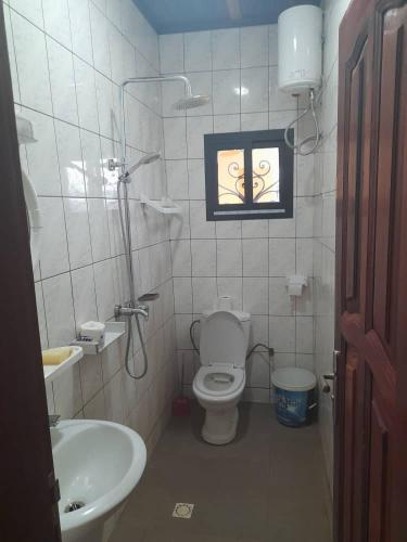 ein Badezimmer mit Toilette und Waschbecken und einem Fenster in der Unterkunft Coubaahala in Jaunde