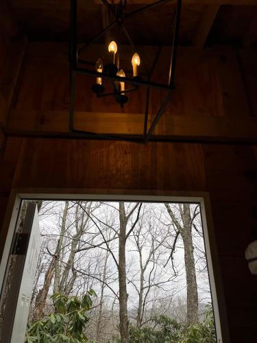 una lámpara de araña colgando sobre una ventana en una cabaña en High Country-The Well House, en Blowing Rock