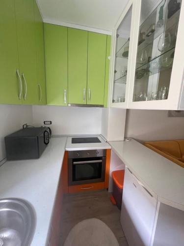 uma pequena cozinha com armários verdes e um lavatório em Studio apartment next to 5* resorts, Golem em Durrës