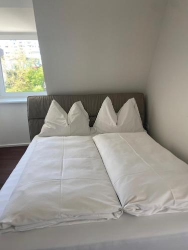 a bed with white sheets and pillows in a room at Das Anton in Gmunden
