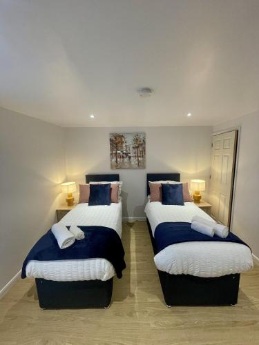 a bedroom with two beds with blue and white sheets at Cozy Cheltenham Accomodation in Cheltenham