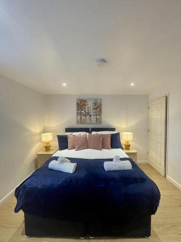 a bedroom with a large blue bed with two lamps at Cozy Cheltenham Accomodation in Cheltenham