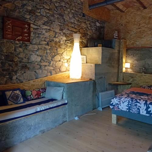 Cette chambre comprend un lit et une lampe sur un mur. dans l'établissement Mas Dupoune avec Piscine & Spa, à Sumène