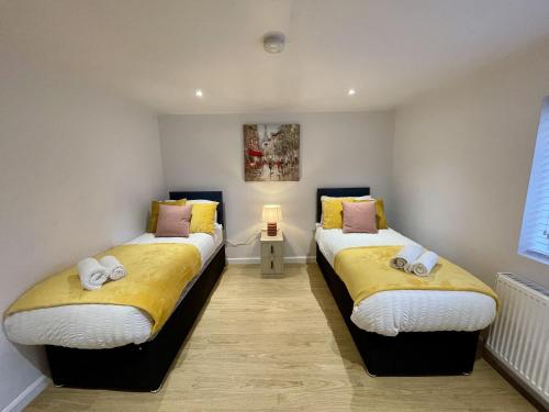 two beds in a room with yellow and white sheets at Cosy House Accommodation in Cheltenham