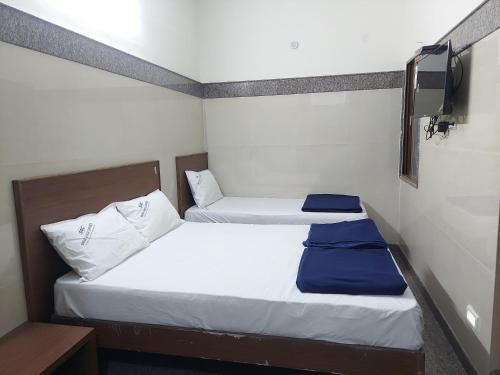 two twin beds in a small room with a tv at Shivaganga Comforts in Bengaluru