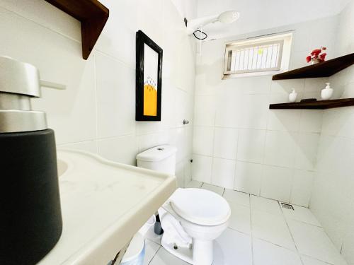 a white bathroom with a toilet and a sink at La Casita Atins in Atins